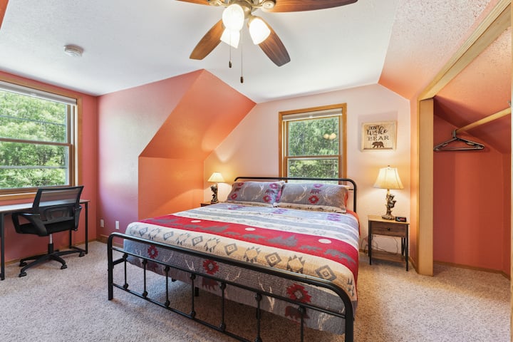 Upstairs bedroom with a king bed, work desk, Roku TV, USB charging ports on lights, dresser, closet with hangers