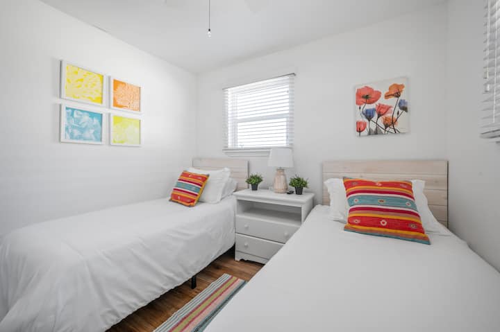 Chumba cha pili cha kulala chenye vitanda viwili vya kushinda, mashuka marefu, feni ya dari na televisheni mahiri.