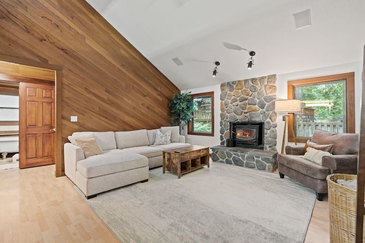 Მისაღებ ოთახს აქვს დიდი სექციური სკამი, არაგაბარიტული სკამი, ყავის მაგიდა, საბნებით სავსე კალათა და შეშის ბუხარი (მოწოდებულია ხე).