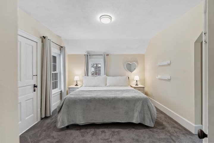 Chumba cha kulala #1, kitanda cha ukubwa wa kifalme na roshani ukiangalia juu ya ua wa nyuma.  Kiyoyozi kinachobebeka kimetolewa. 