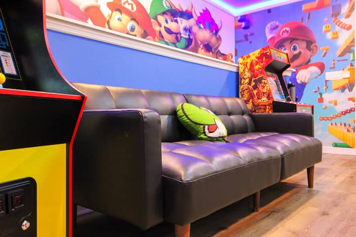Повишете нивото си във вълнуващата стая за игри на Супер Марио! Това пространство разполага с аркадни машини, маса за футбол, тематично изкуство на стената, неонови светлини, голям телевизор, забавен декор и оживена геймърска атмосфера – идеално за завладяващо приключение в Гъбеното кралство с забавления