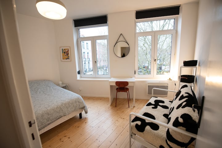 Bonita habitación con cama doble, espacio de trabajo y sofá. Vistas a una plaza arbolada.