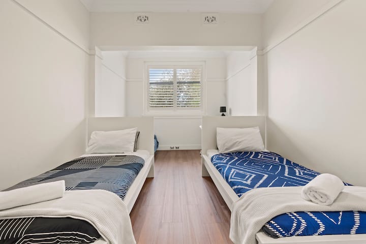 这间大卧室配有两张大单人床、储物柜、一张办公桌和沙发