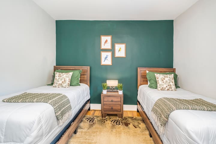 2つのツインベッドを備えたRaleighの自然をテーマにした寝室。 ナイトテーブルの一番上の引き出しにスリープマシンをご用意しています。