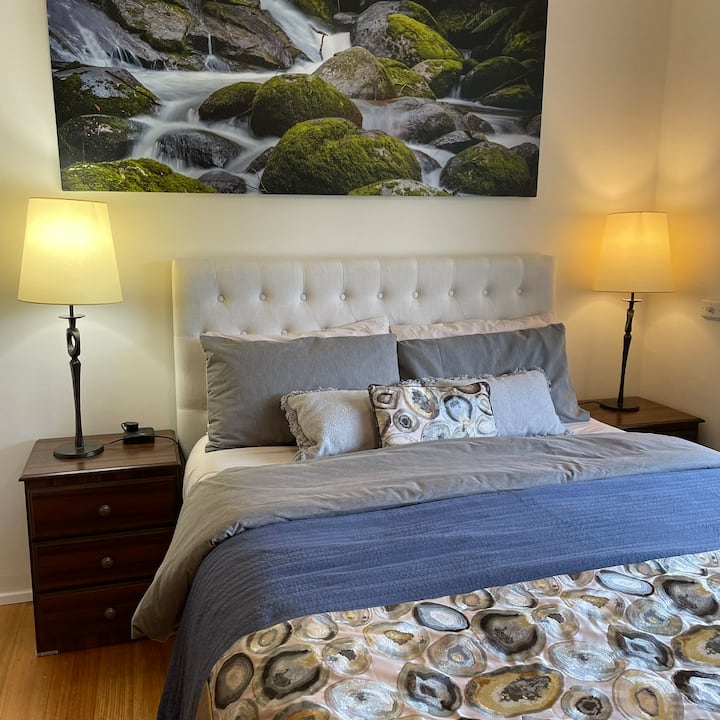 The generous bedroom boasts a soft-upholstered headboard that anchors the space, perfectly complemented by sleek bedside lighting to set a tranquil evening mood.