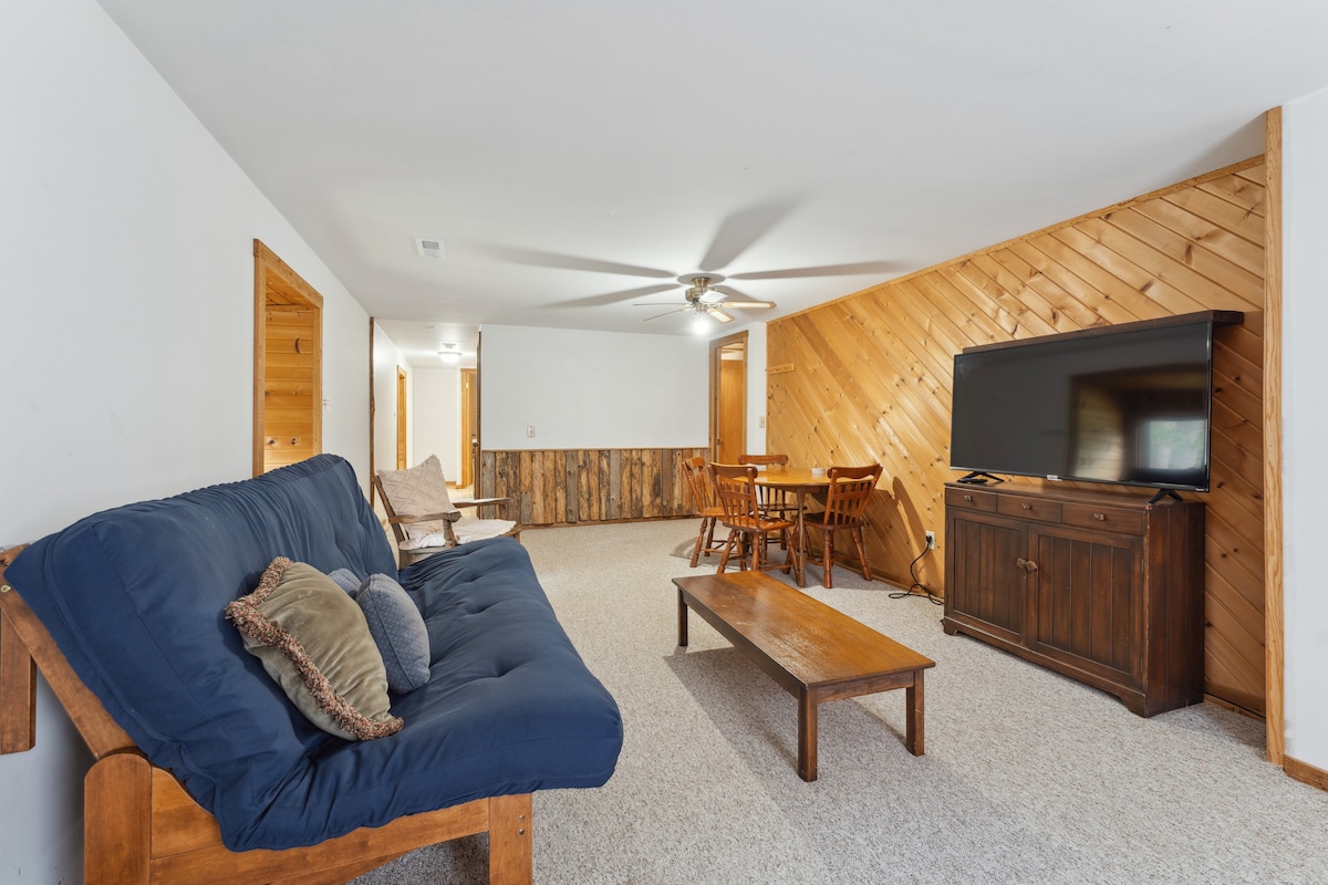 Loft de cabaña en la planta superior con futón queen, Roku TV, mesa y sillas, y espacio adicional para relajarse. 