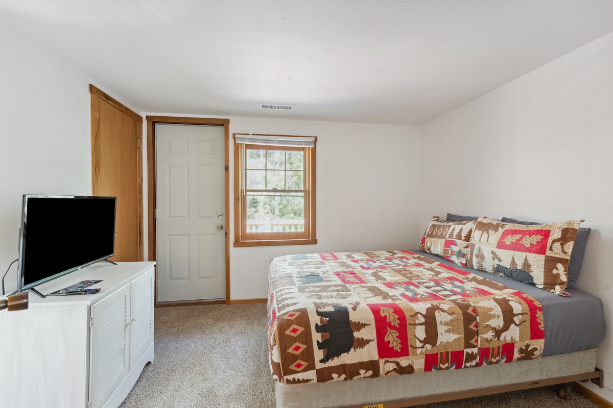 La cama completa de la cabaña de arriba incluye TV Roku, cómoda, despertador con cargador USB, ventilador portátil, almohada y mantas adicionales, armario con perchas y acceso al balcón.