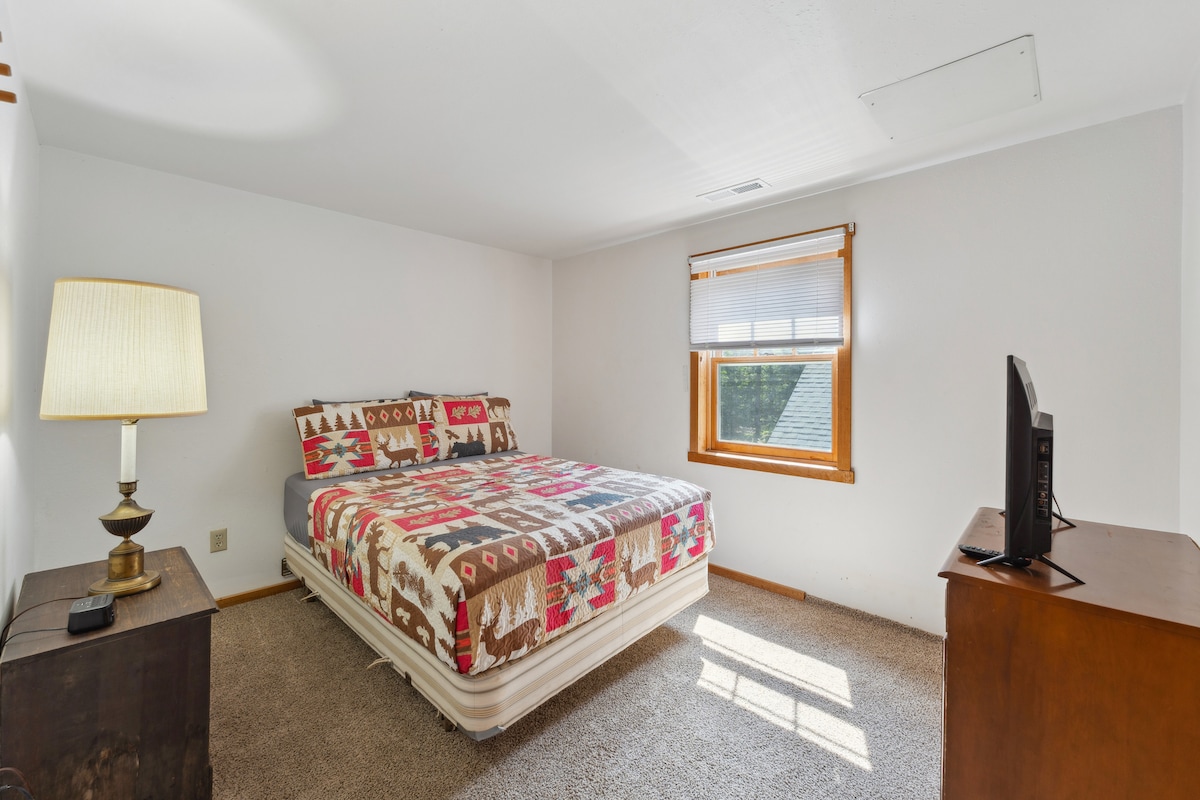 La cama completa de la cabaña de arriba incluye TV Roku, cómoda, despertador con cargador USB, ventilador portátil, almohadas y mantas adicionales, y armario con perchas.