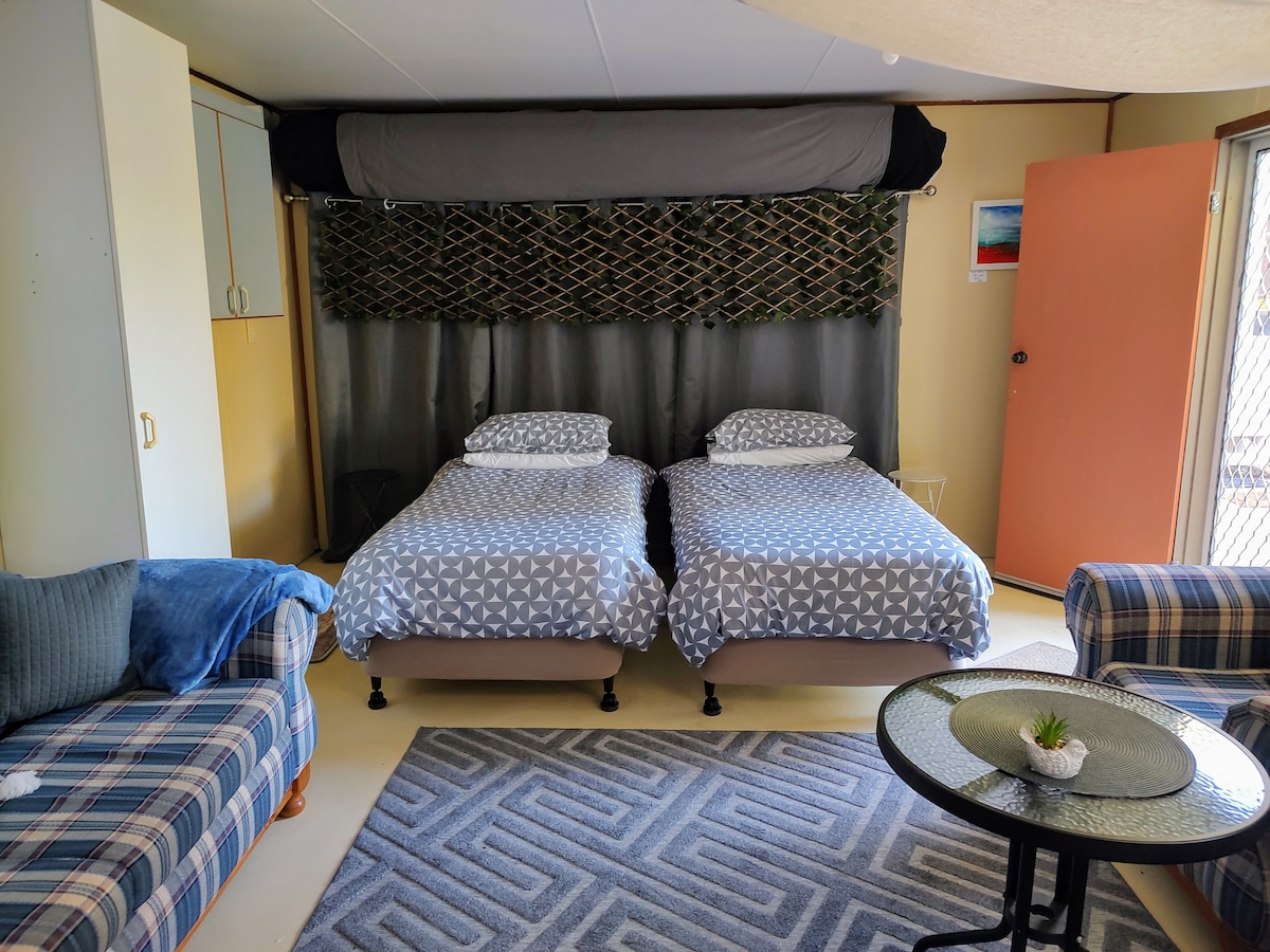 Un tranquilo descanso ubicado en el jardín trasero.  Las dos cómodas camas individuales hacen que el estudio sea ideal para amigos, familiares o compañeros de viaje que prefieren su propio espacio.