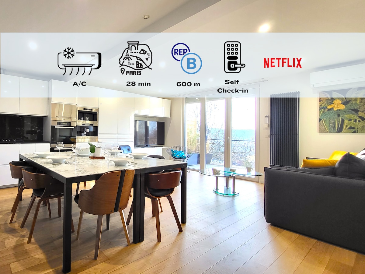 A modern kitchen and living area is featured, showcasing a large dining table surrounded by wooden chairs. Floor-to-ceiling windows allow natural light to fill the space, providing access to the terrace. A cozy sofa and contemporary decor enhance the welcoming ambiance.