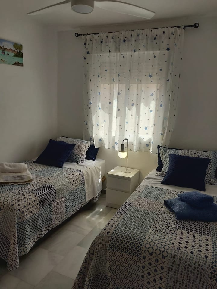 Спална соба во МАЛАГА, со два единечни кревета од 90 и тавански вентилатор.