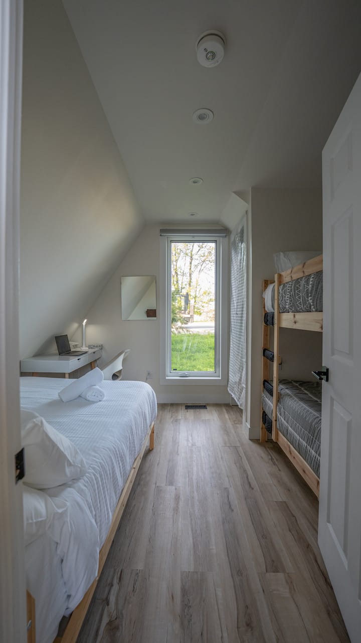 غرفة نوم مشرقة ومريحة مثالية للعائلات أو المجموعات الصغيرة! يضم سريرًا مريحًا بحجم كوين وسريرين صغيرين ومساحة عمل. استمتع بالضوء الطبيعي من النافذة الكبيرة مع إطلالات هادئة. مسكن هادئ للاسترخاء أو العمل أو الاستجمام بعد مغامراتك.
