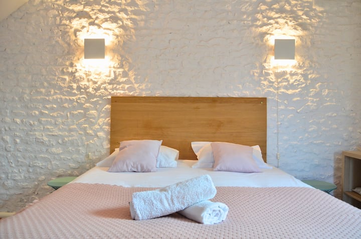 Zona notte di Marguerite con un letto matrimoniale 160 cm e un letto singolo. Un arredamento fresco, bucolico e vintage. Vista sul giardino dalla finestra. Questa camera è organizzata in una suite padronale con doccia all'italiana, WC e lavandino.