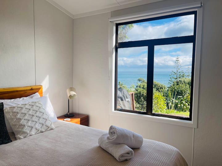 El dormitorio 1 tiene una generosa cama tamaño queen con un cómodo cubrecolchón de espuma viscoelástica, lámparas de mesita de noche para esa acogedora lectura a la hora de acostarse, increíbles vistas a Kapiti Island, una televisión inteligente y un calentador ecológico para mantenerte caliente y cómodo en invierno.