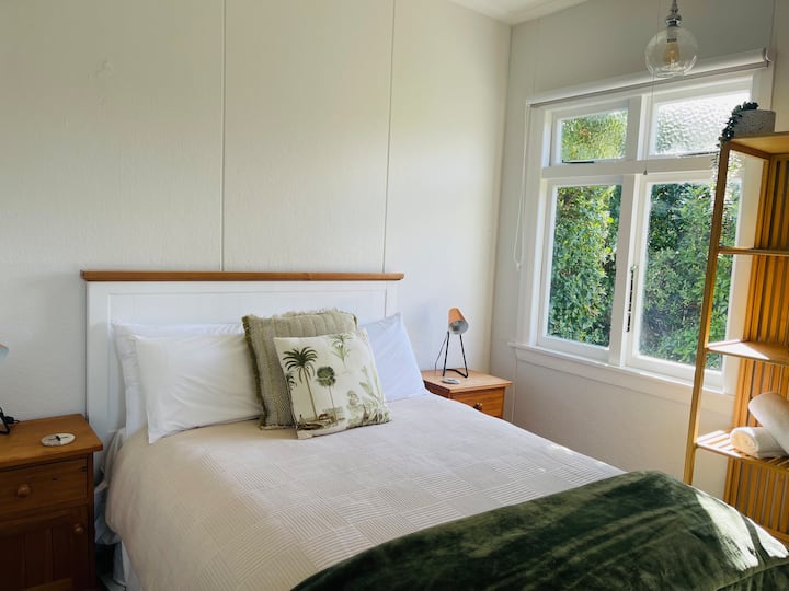 El dormitorio 2 tiene una generosa cama doble con un bonito y cómodo cubrecolchón, lámparas de mesita de noche para esa acogedora lectura a la hora de acostarse, un calentador ecológico para mantenerte agradable y cálido en invierno y una vista relajante de arbustos.