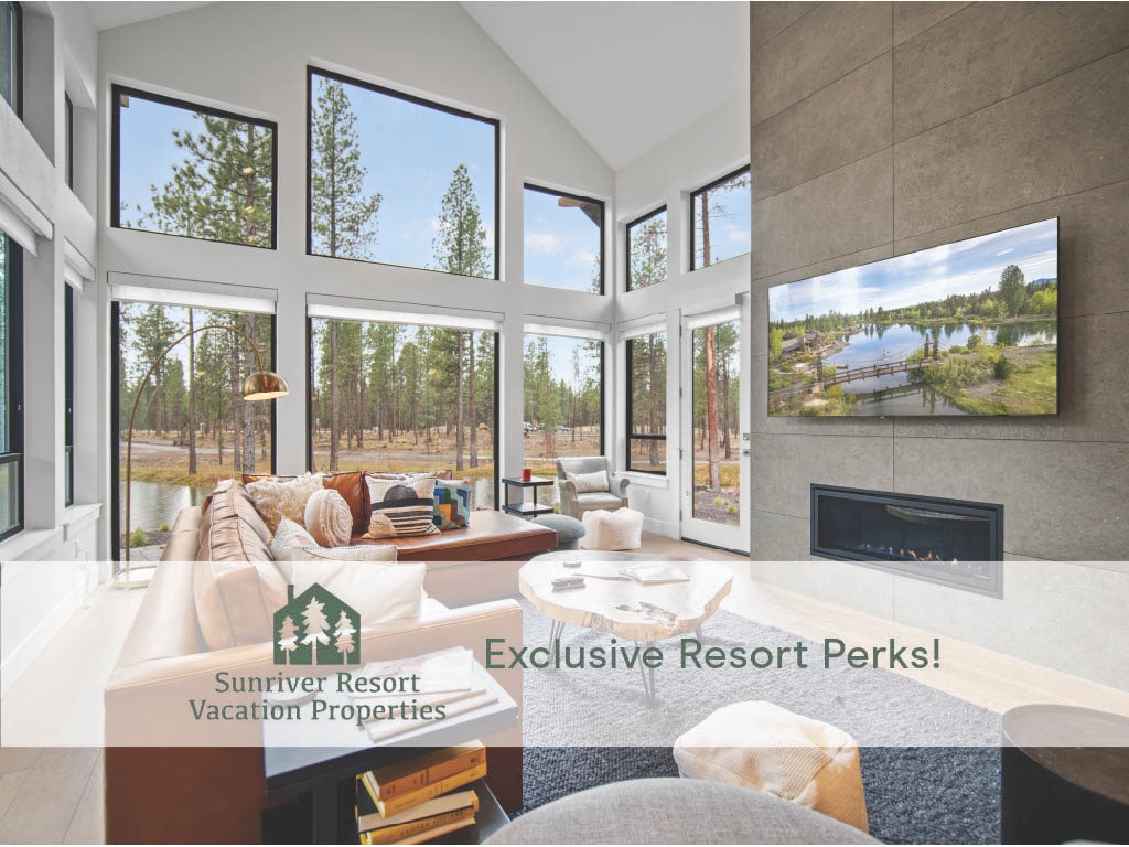 A spacious great room is filled with natural light coming from large floor-to-ceiling windows. A comfortable sofa is arranged around a coffee table, and a gas fireplace adds a calming feature to the room. A television mounted on the wall displays a scenic view of the surrounding landscape.