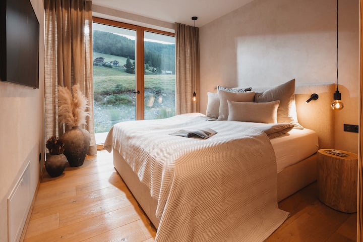 Die Bach-Suite | das Schlafzimmer mit der besonderen Aussicht: Morgens erwachen mit dem Blick auf den Oswalder Bach, die Almwiesen und das historische Weger Stadl – sanftes Wasserrauschen inklusive.

