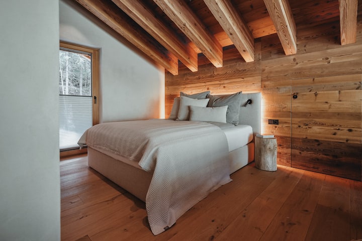 Die Dach-Suite | Unsere höchste Suite - mit Galerie-Blick in den Wohnraum, den Wald und über die Almwiesen hinaus. Hier finden bis zu vier Personen Platz – darunter zwei im extrabreiten Design-Stockbett. En-Suite Bad und TV sind ebenfalls an Bord. 