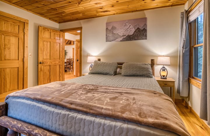 Welcome to the spacious guest bedroom! Featuring a queen-sized luxury mattress, rustic nightstands with lamps, a large closet, Smart TV, and a cozy rocking chair, this room offers the perfect retreat for relaxation and comfort.