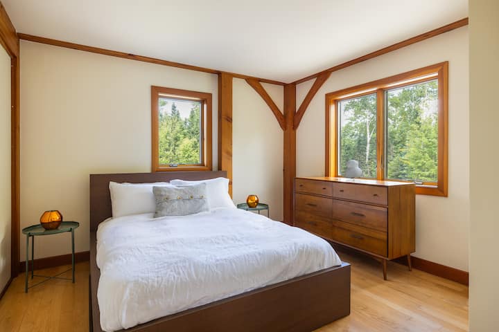 A warm, restful room with forest views and gentle light—perched above the drive, perfect for spotting arriving friends without leaving your cozy retreat.