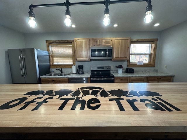 A spacious kitchen is presented with wooden cabinetry and a large countertop featuring the 'Off The Trail' logo. Modern appliances, including a stove, microwave, and refrigerator, are equipped, with natural light filtering through the shades of the nearby windows.