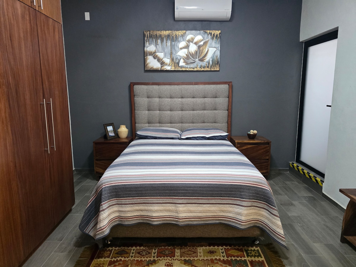 Descansa en nuestra habitación, donde una cómoda cama matrimonial te espera, junto con aire acondicionado y un espacioso closet de madera para tu comodidad.