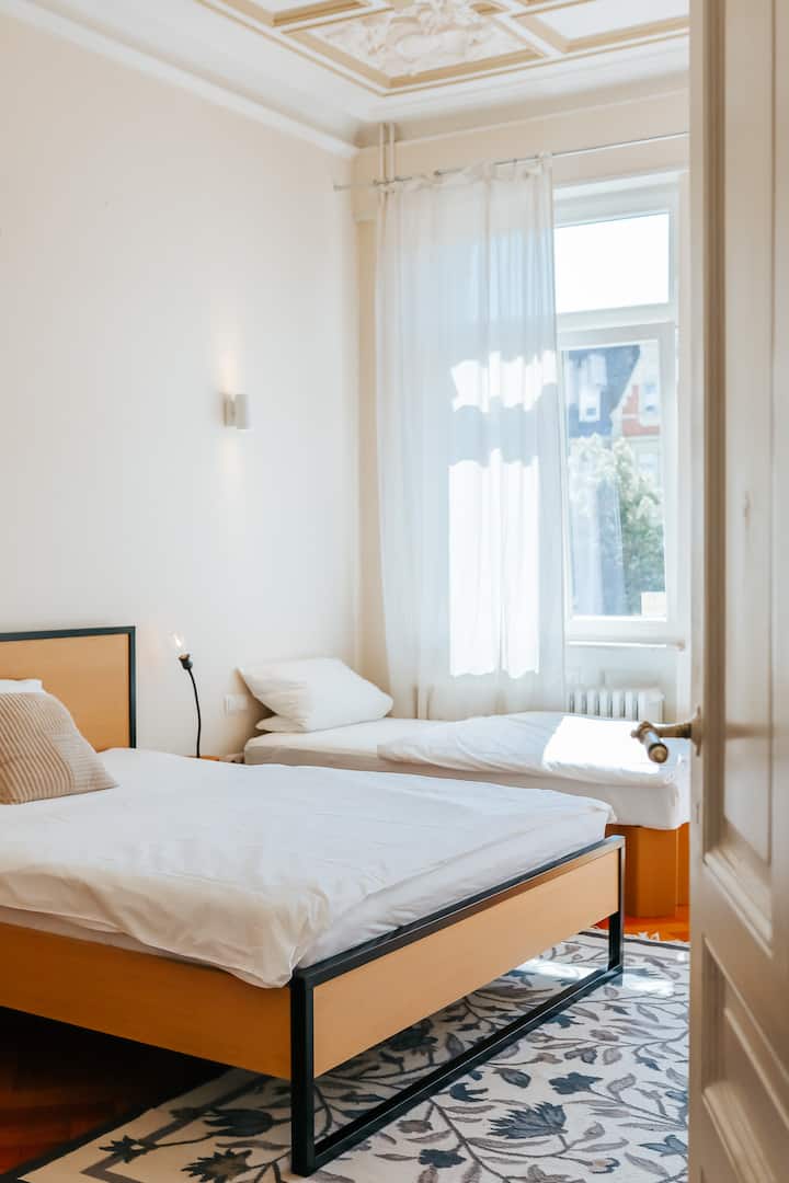 Dormitorio con cama queen size de 160 cm + cama individual adicional de 90 cm en un elegante edificio antiguo. 

Uno de los dos balcones: un oasis de tranquilidad en medio de la ciudad, ideal para respirar hondo.