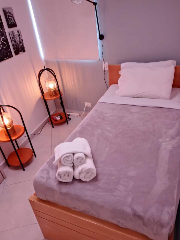 Sumérgete en la calidez de esta habitación con iluminación tenue, cuadros decorativos y una cama acogedora. Ideal para relajarte después de un día explorando. ¡Reserva tu estancia y vive la experiencia!