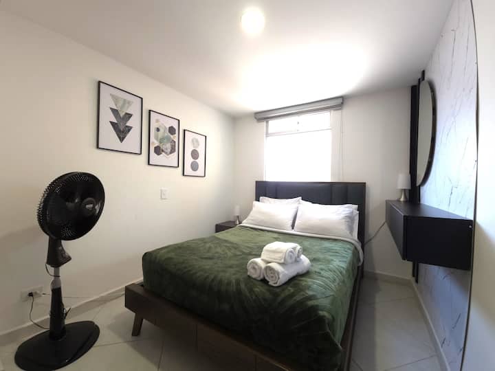 Descansa en una habitación moderna y acogedora. Cama cómoda, espejo, repisa flotante y una decoración que invita al relax.