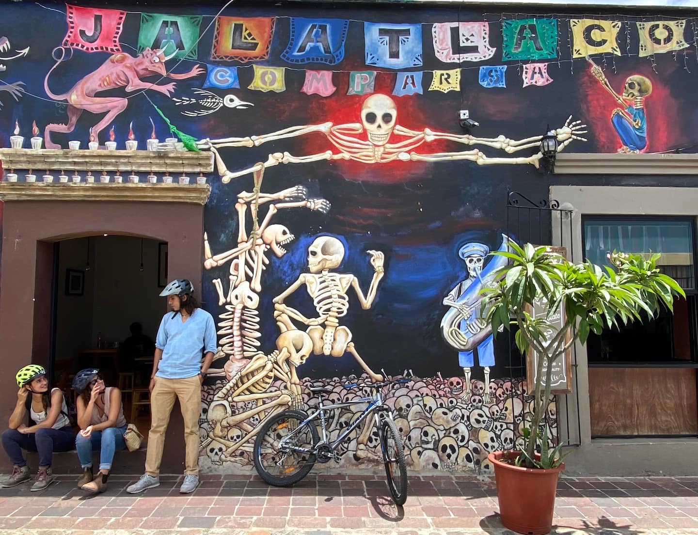 two woman in front of a colorful mural in oaxaca city on a street art bike tour