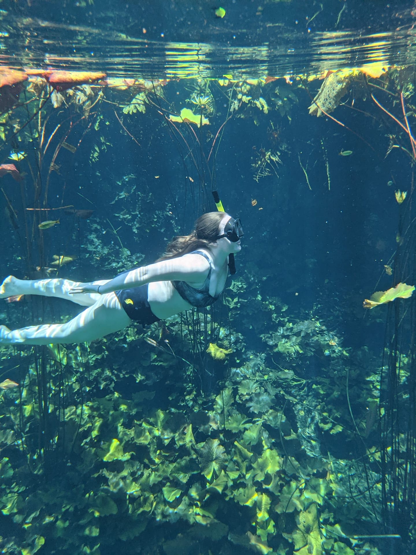 man and woman in orange life jackets walking through one of the best tulum cenotes in mexico, located underground in a cave | Cenotes Tours Tulum