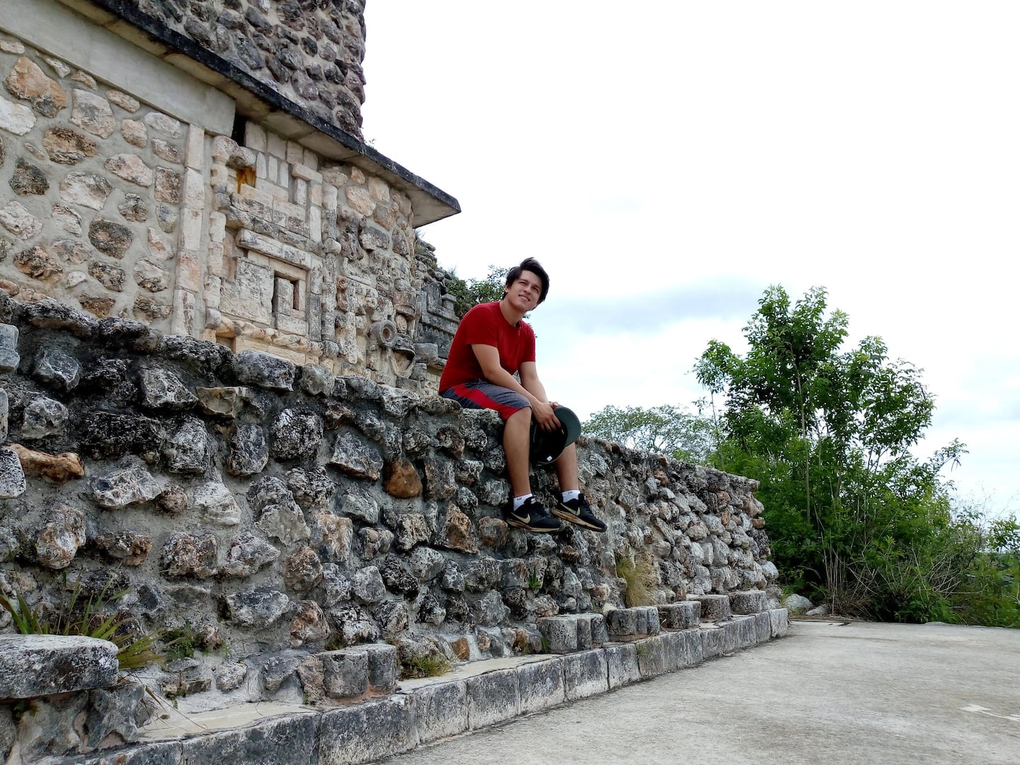 man in red posing in uxmal ruins