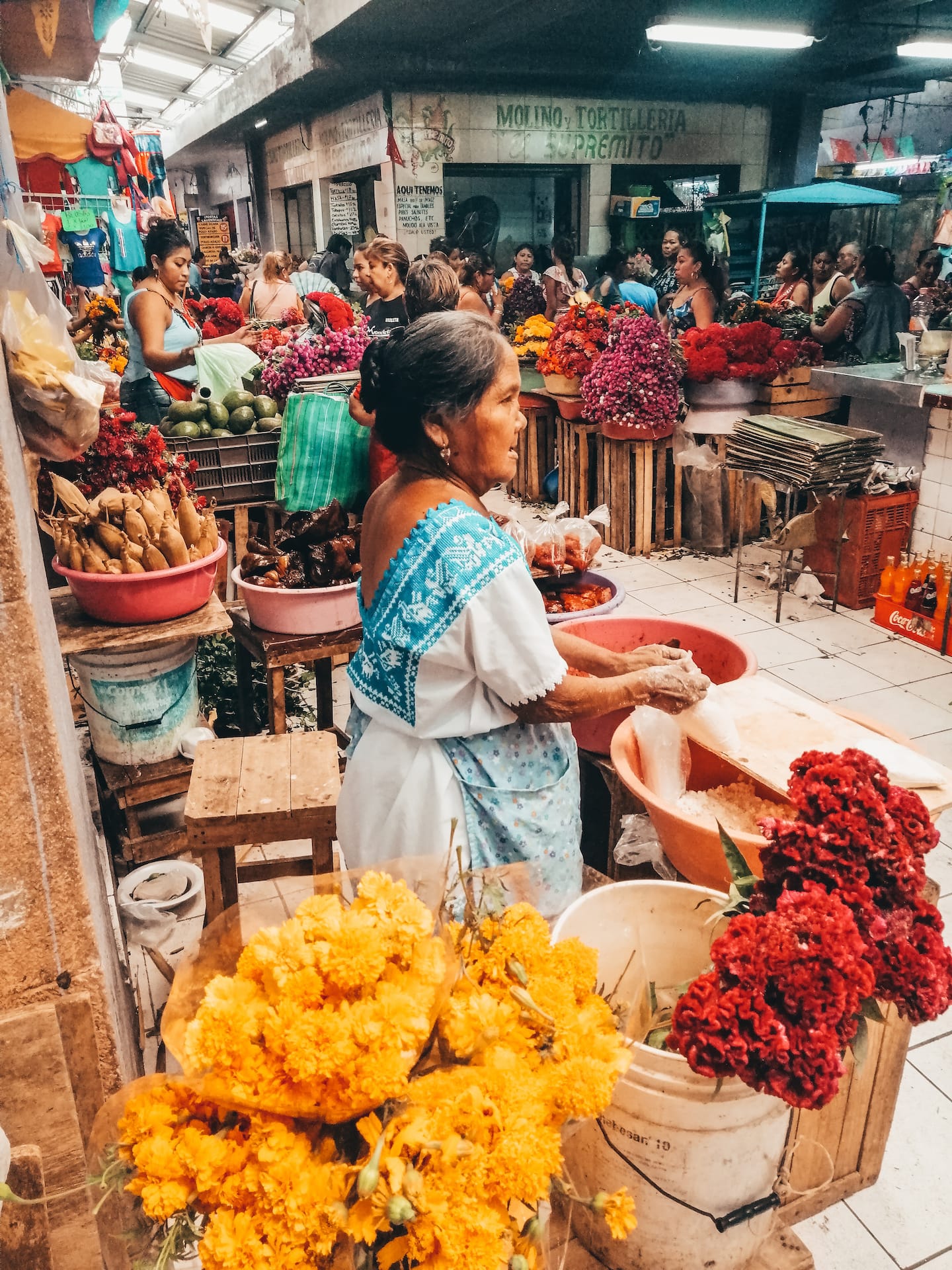 Merida tours: A mayan woman in traditional dress selling flowers in a merida mexico market