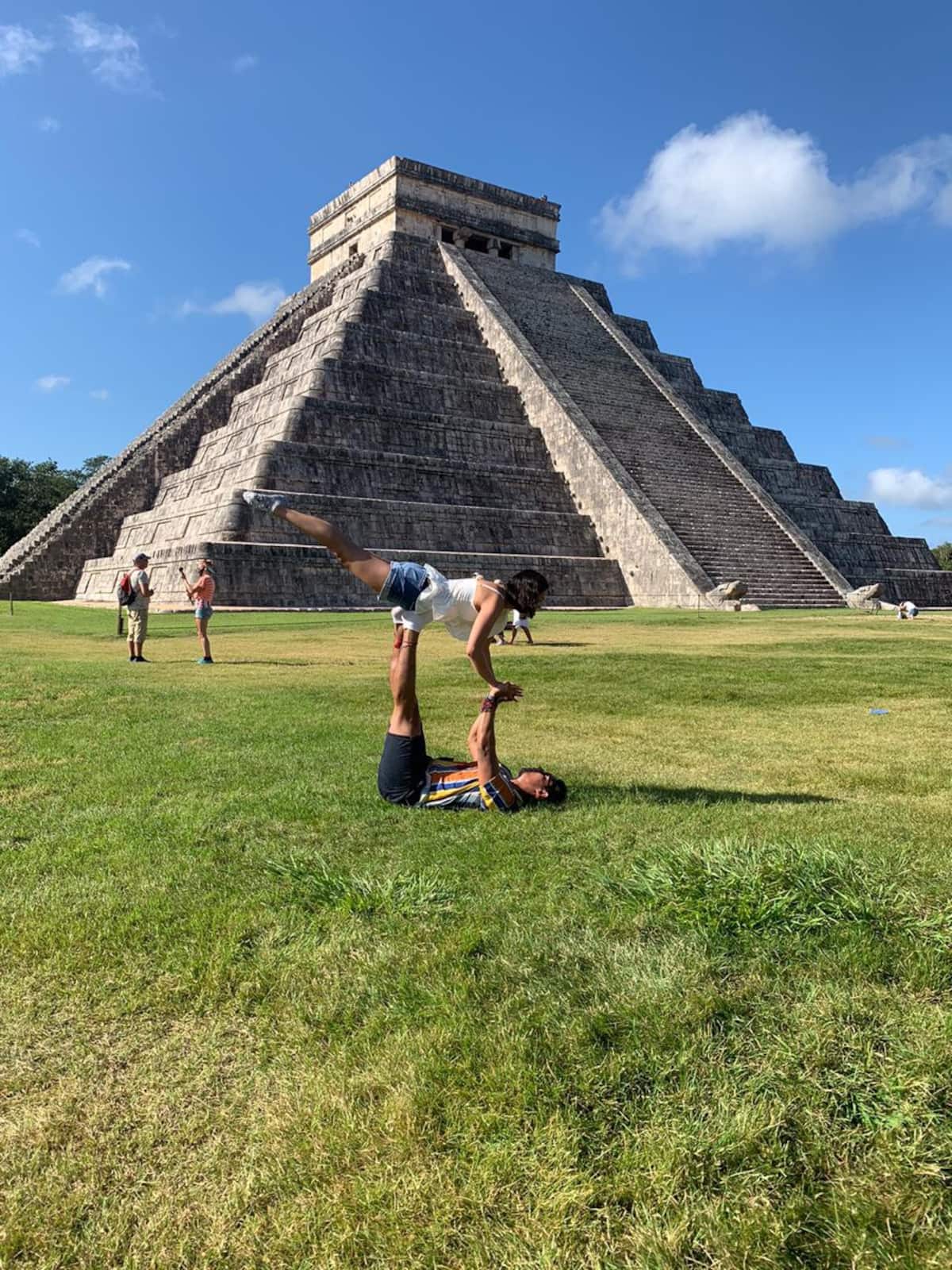 Merida tours: Man and Woman doing acro yoga in front of Chichen Itza Mayan Ruins in Mexico