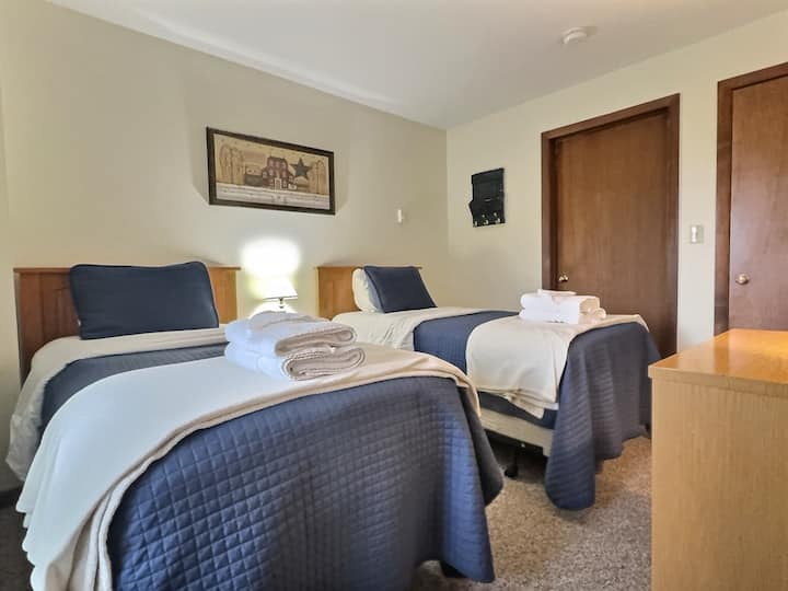 Ingia kwenye chumba chetu cha kulala chenye starehe kisicho na kitanda kimoja, bali vitanda viwili vya mtu mmoja.