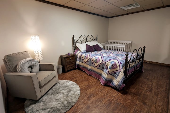 Downstairs left bedroom featuring queen size bed, crib and cozy rocking/nursing chair.
