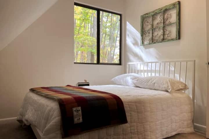 Nestled upstairs, this cozy bedroom features a full bed and rustic furnishings perfect for unwinding at the end of the day tucked away in the serenity of the mountains.
