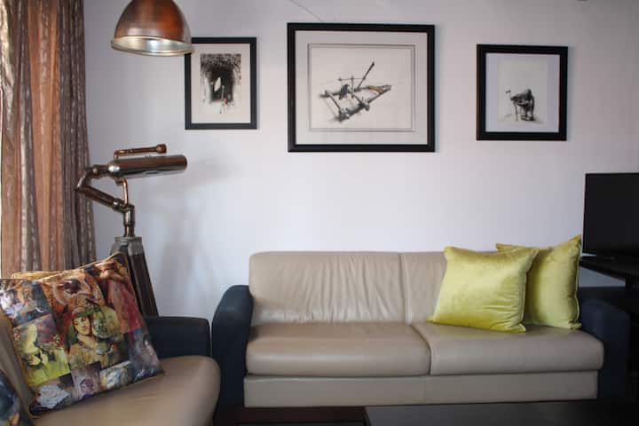 Ontspan in de woonruimte beneden, omringd door prachtige kunstwerken, en loop naar je eigen patio en braai-ruimte.