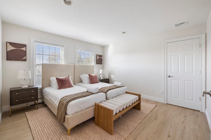 Ფართო საძინებელი ლუქს-კლასის 7-საძინებლიან საცხოვრებელში მომხიბვლელ ჩესტერში, რომელშიც არის ორი ერთადგილიანი საწოლი, დიდი ფანჯრები ბუნებრივი განათებით და ორი საწოლისპირა მაგიდა ელეგანტური ლამპებით მყუდრო, მშვიდი ატმოსფეროსთვის.