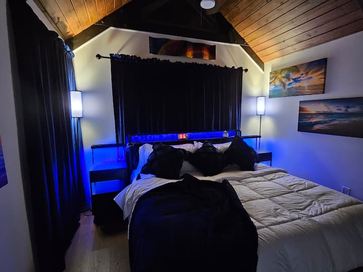 Კეთილი იყოს თქვენი მობრძანება Blue Bayou საძინებელში #3. ამ ოთახში არის დიდი საწოლი ბალიშის ზედაპირით და ორი სტილის ბალიში, კარადა საკიდებით და ლურჯი ხავერდის ფარდები ბრტყელეკრანიანი ტელევიზორით.  Აქცენტის განათება თავსაფარზე და ღამის სადგამები USB დამტენი პორტებთან ერთად 