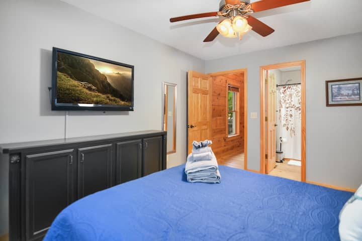 Main level bedroom room with smart TV, queen size bed, attached full bathroom