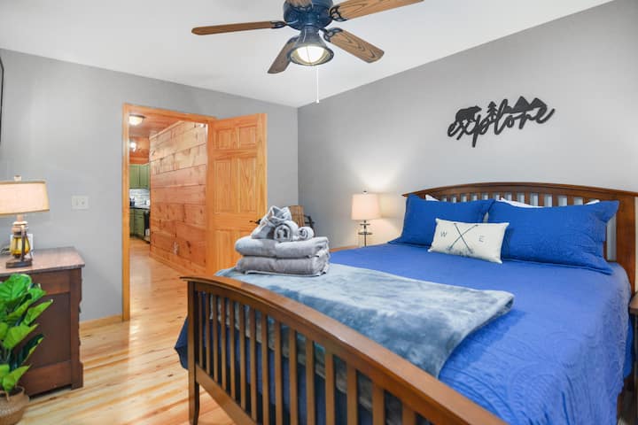 Main level bedroom 2 with queen size bed, mounted smart screen TV, ceiling fan and clothing storage