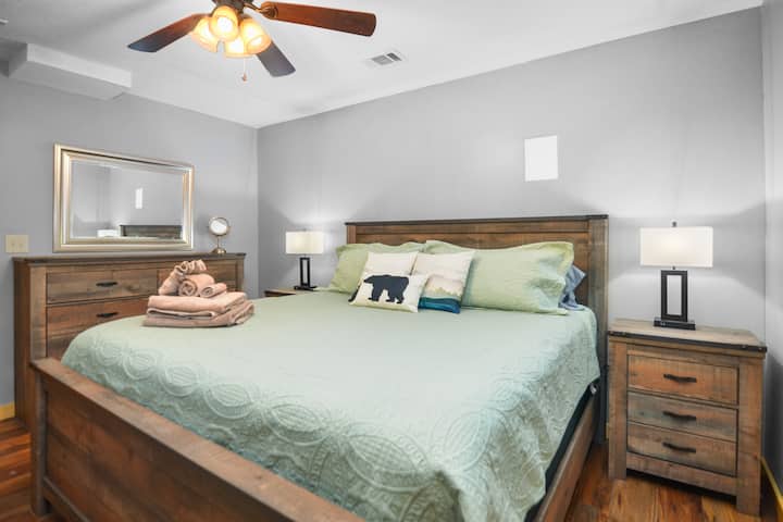 Lower level bedroom with King size bed with rustic decor, ceiling fan and dresser for clothing storage