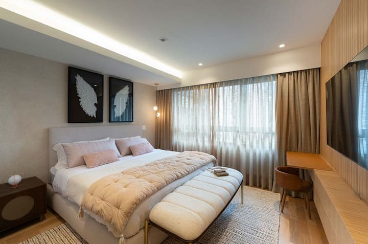 Habitación principal con cama king y monitor de TV de pantalla plana, estación de trabajo de cuero que se convierte en tocador de maquillaje