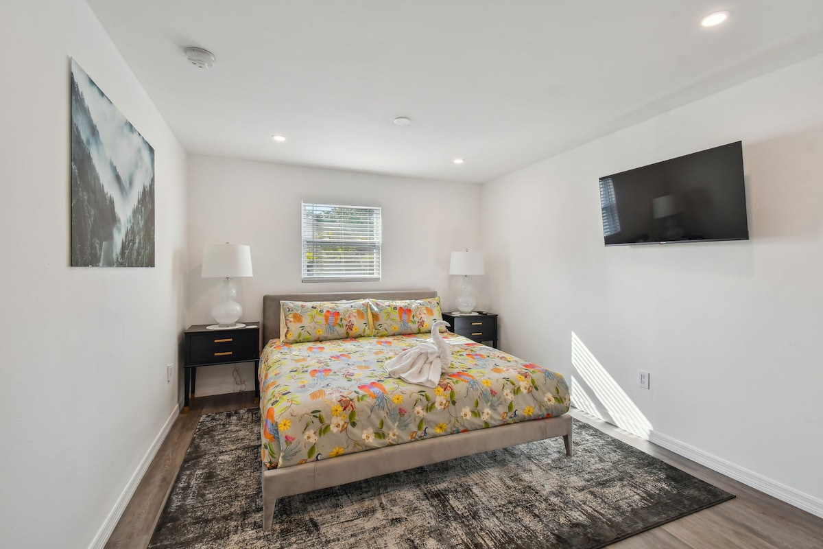 Დიდი საძინებელი 43-დუიმიანი სმარტ-ტელევიზორით, რომელიც გადაჰყურებს ბუხარს