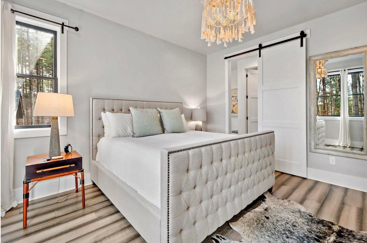 主卧配备加大双人床，卫生间的滑动门可见。