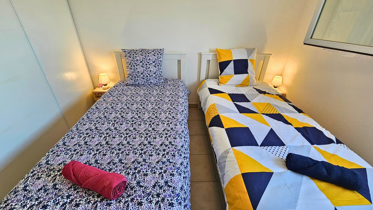 Привлекателна стая с всекидневно спално бельо, идеална за моменти на релаксация. Представете си, че сте тук, готови да си починете след ден на проучване, меката светлина на лампите, които добавят успокояващо настроение.