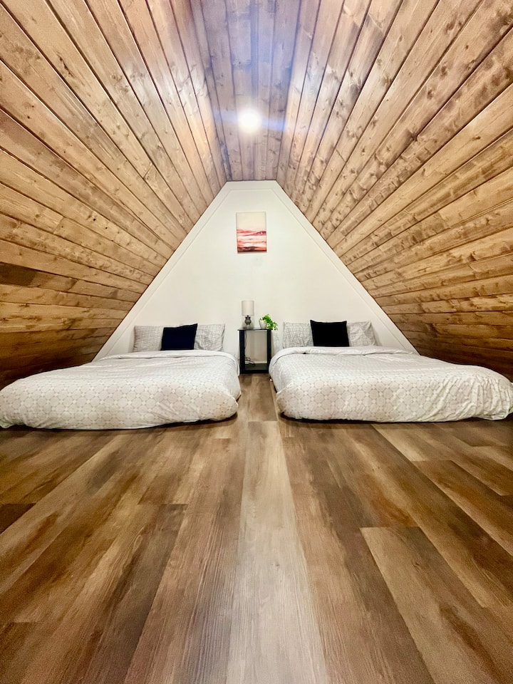 ห้องนอนสไตล์ลอฟท์ชั้นบนพร้อมเตียงใหญ่ 2 เตียง