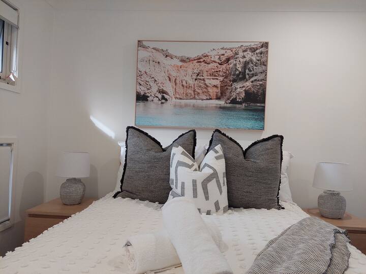 ในห้องนอนที่ 2 มีเตียงคู่พร้อมโต๊ะข้างเตียงและไฟอ่านหนังสือพร้อมพื้นที่เพียงพอสำหรับข้าวของของคุณ