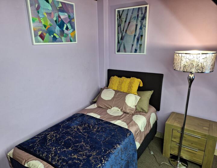 una cama individual en el segundo dormitorio con seda y sábanas de algodón; lámpara con respaldo de batería